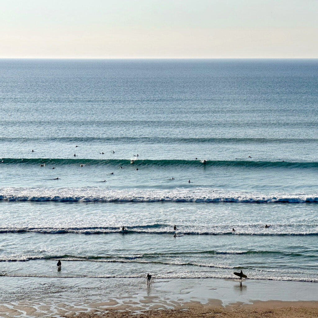 Waves at beach with surfers in the sea